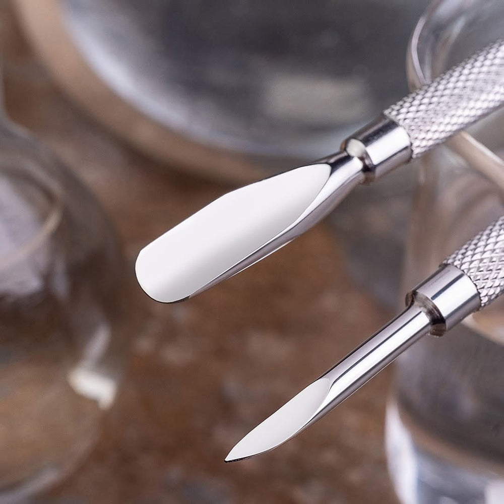 Close-up of a pair of silver cuticle pusher white handles on a blurred background.